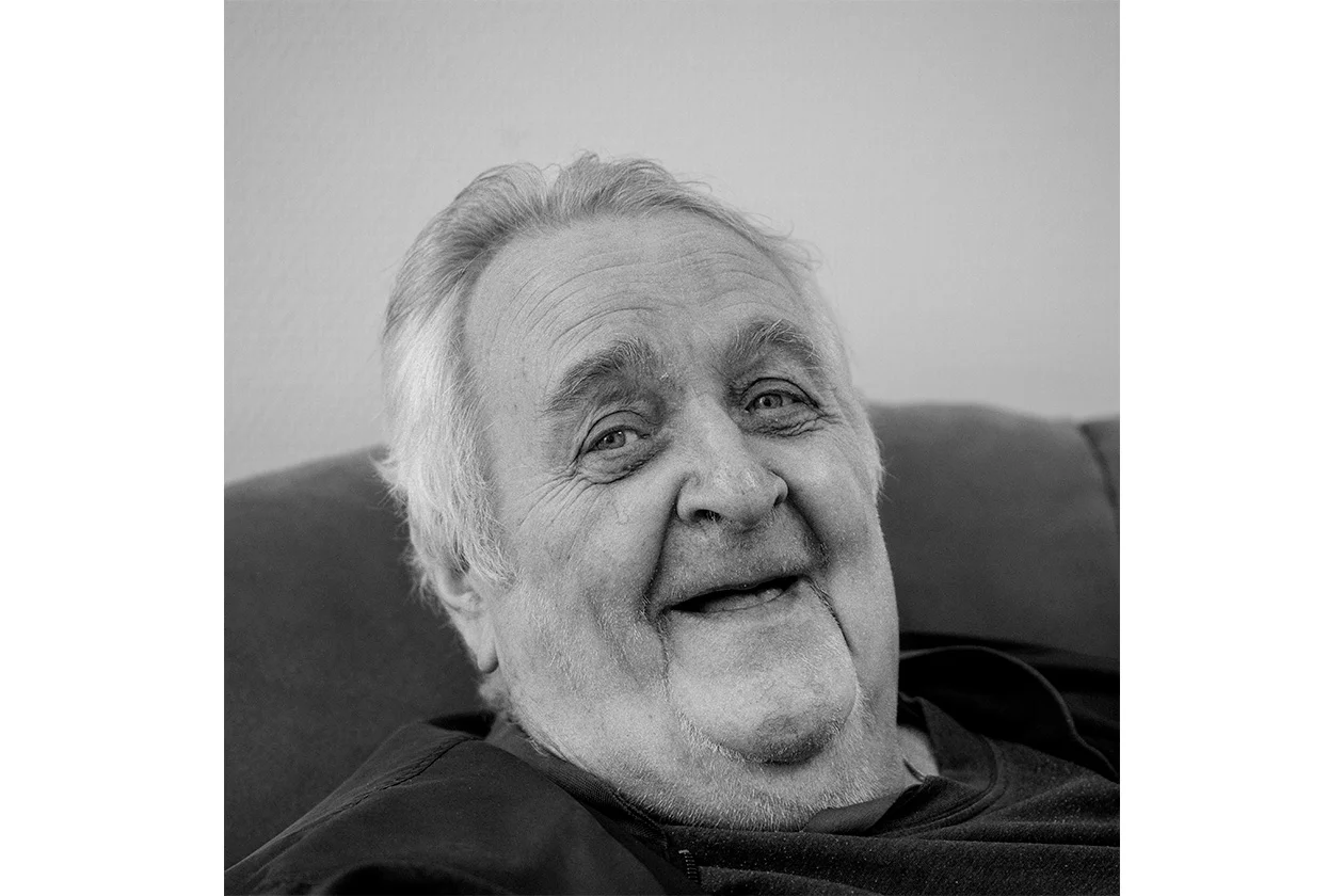Portrait noir et blanc d'un homme âgé souriant tendrement sur un canapé