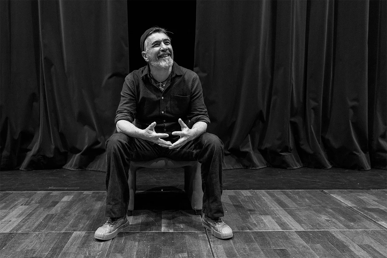 Portrait noir et blanc d'un homme barbu assis sur la scène d'un théâtre