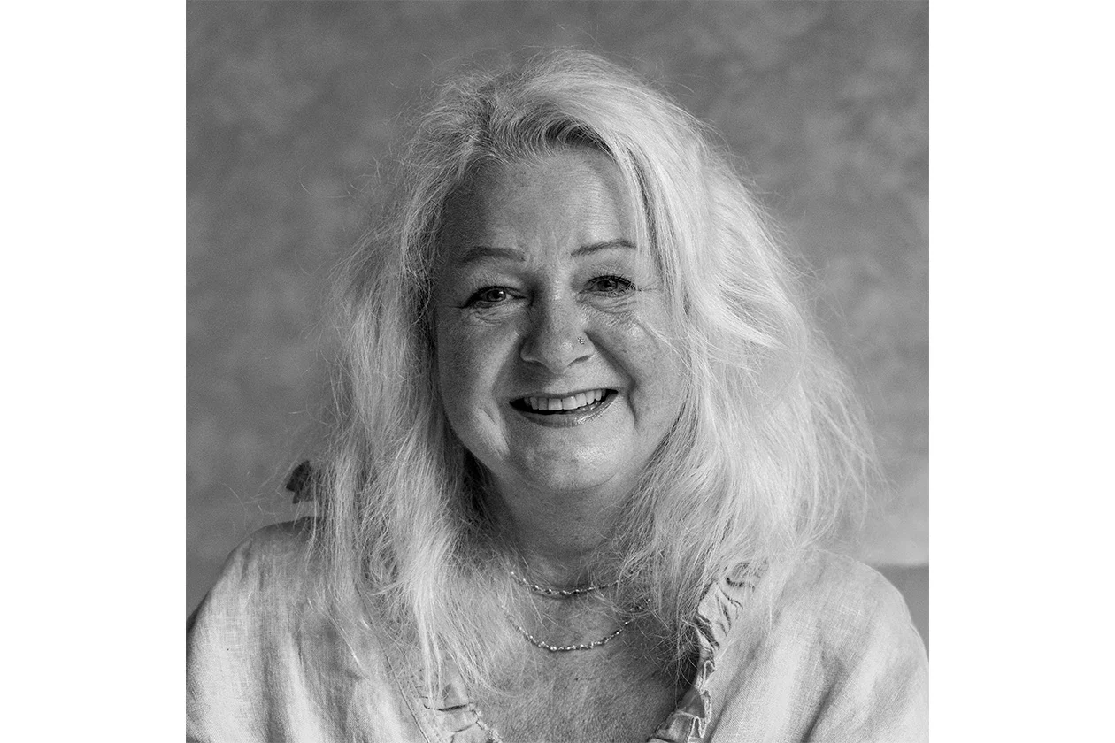 Portrait noir et blanc d'une femme aux cheveux blancs ondulés, sourire chaleureux