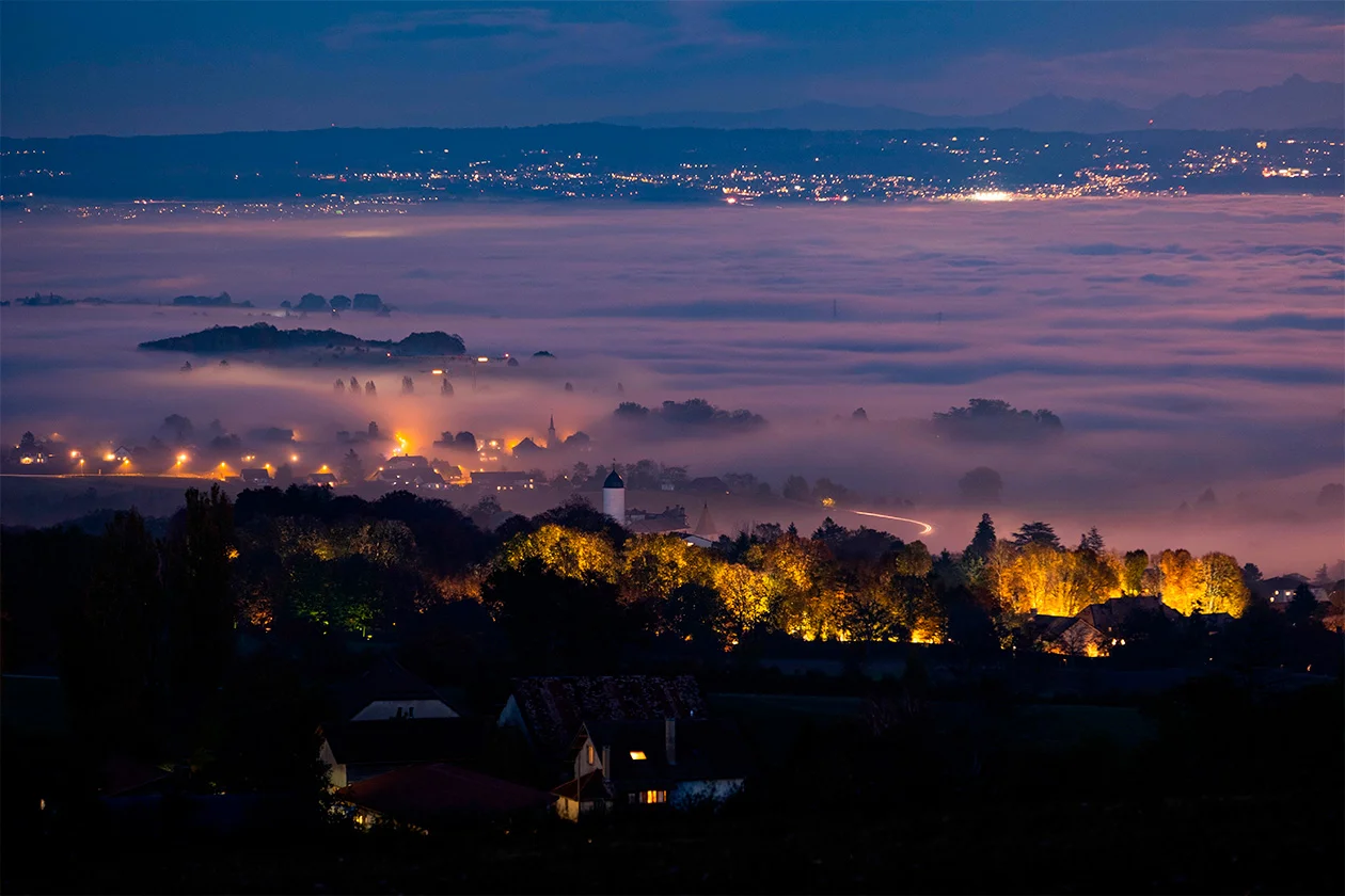 Village suisse dans une brume nocturne dorée illuminée par les lampadaires