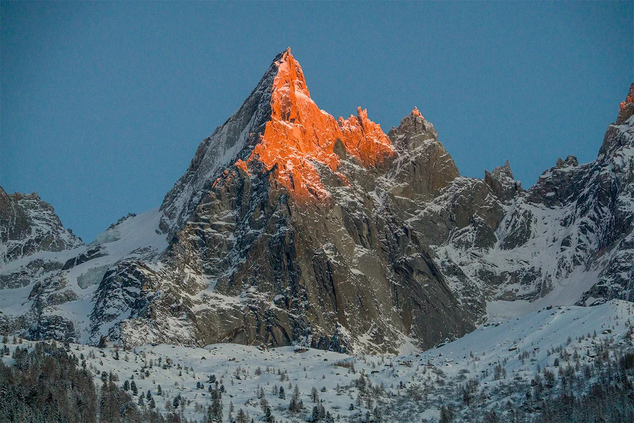 Aiguille des Drus illuminée d'orange au coucher de soleil, sommet rocheux des Alpes