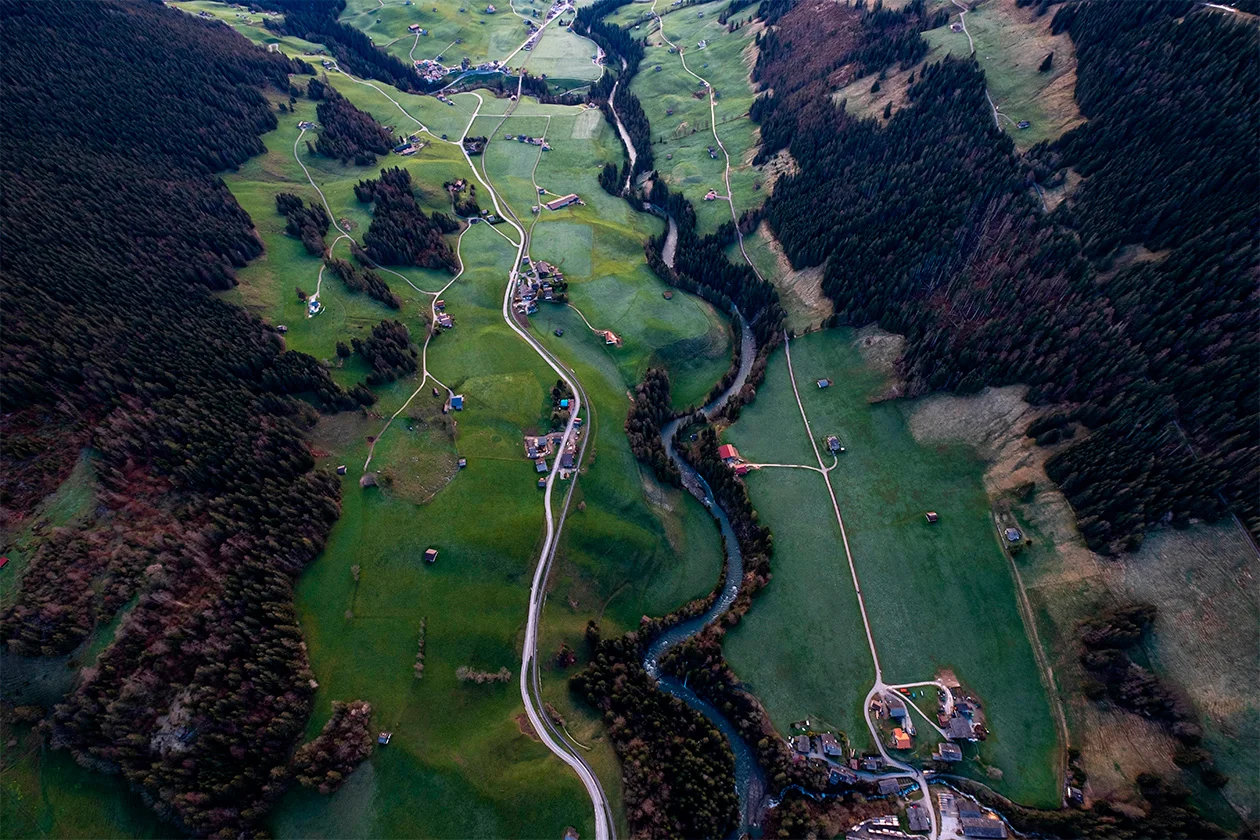 Vue aérienne d'une vallée verdoyante traversée par une rivière sinueuse, Alpes
