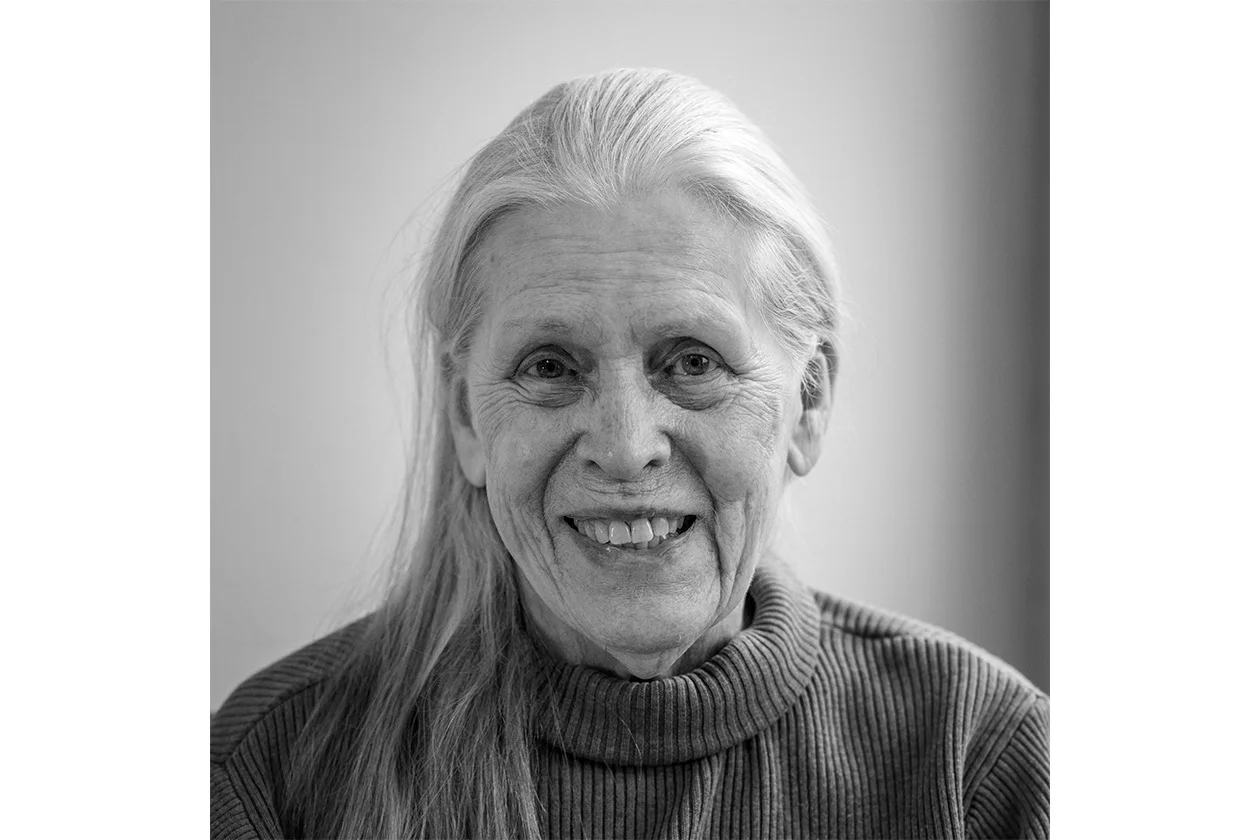 Portrait noir et blanc d'une femme âgée aux longs cheveux blancs, sourire chaleureux