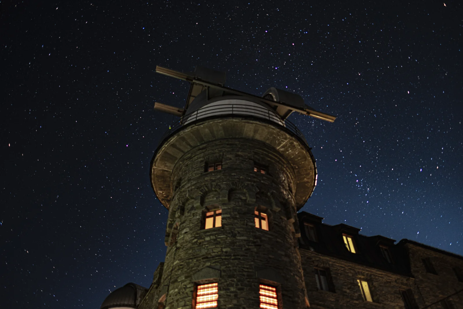 Tour-observatoire en pierre éclairée sous un ciel étoilé, photographie de nuit