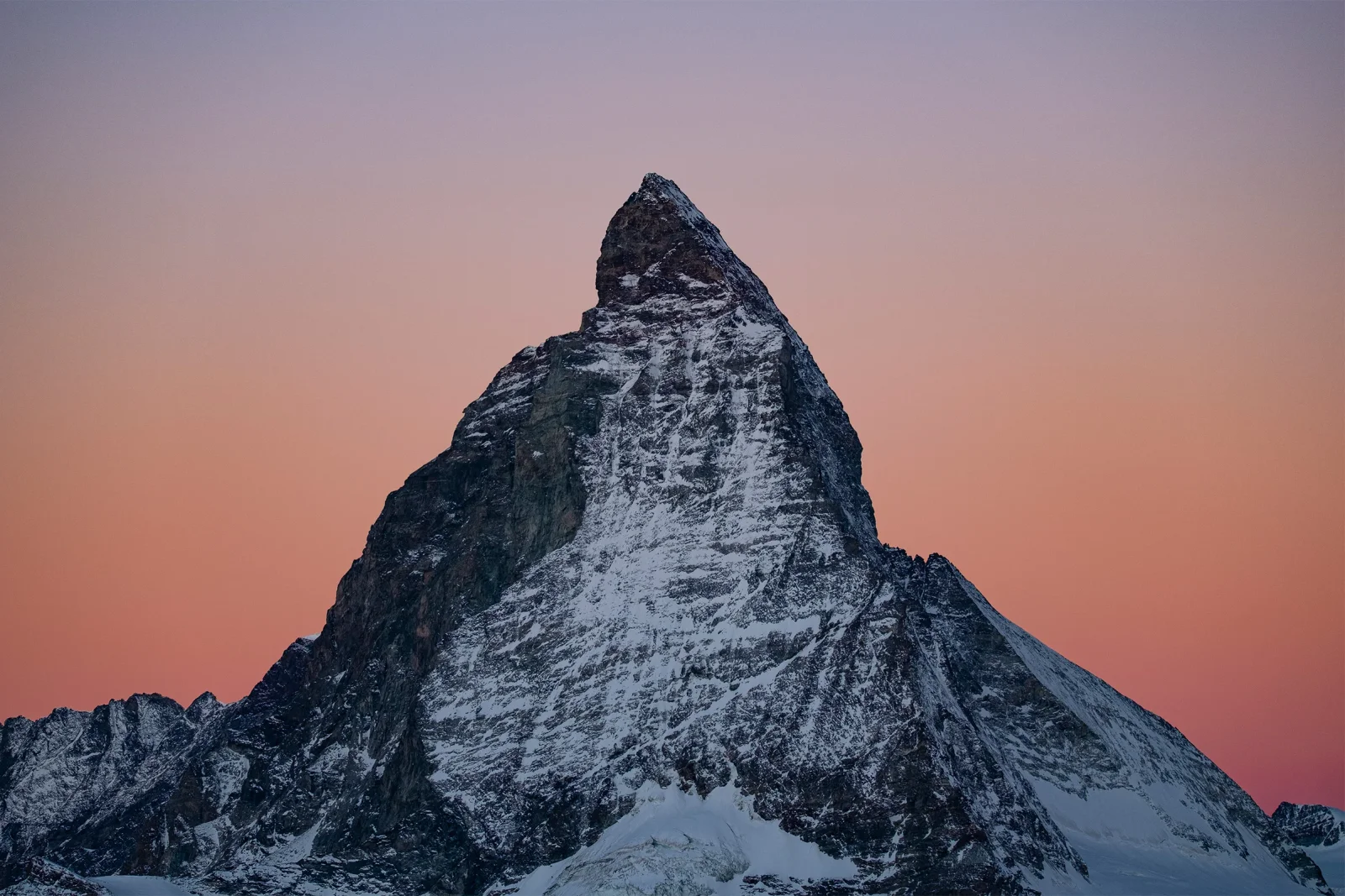 Le Cervin se découpant sur un ciel rose au coucher de soleil, sommet enneigé