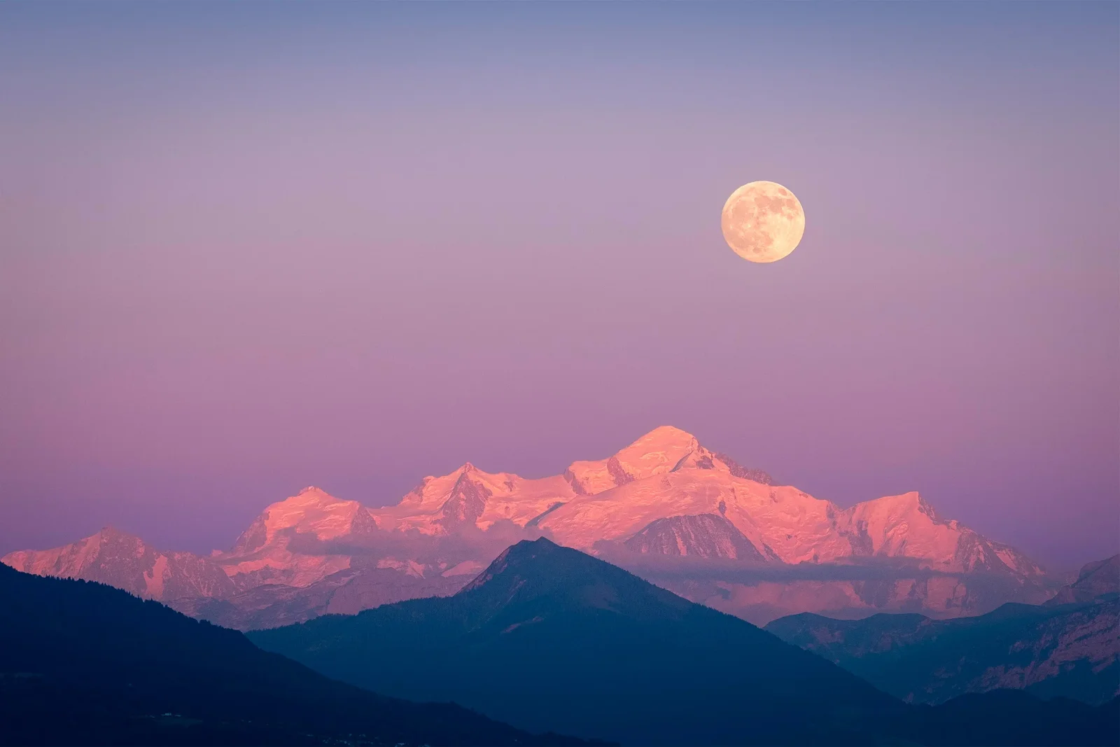 Pleine lune surplombant le Mont-Blanc rosé au crépuscule, ciel violet et lavande