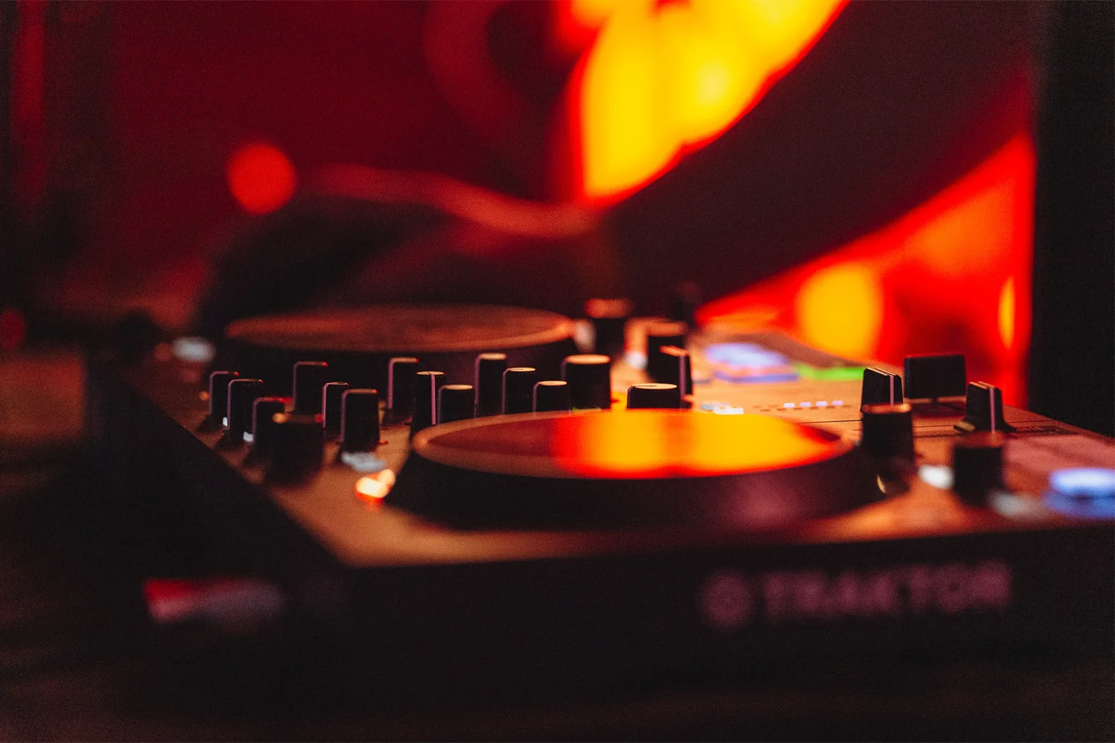 Platine de mixage DJ dans une ambiance lumineuse rouge — photographie sur mesure par Yann Lepora