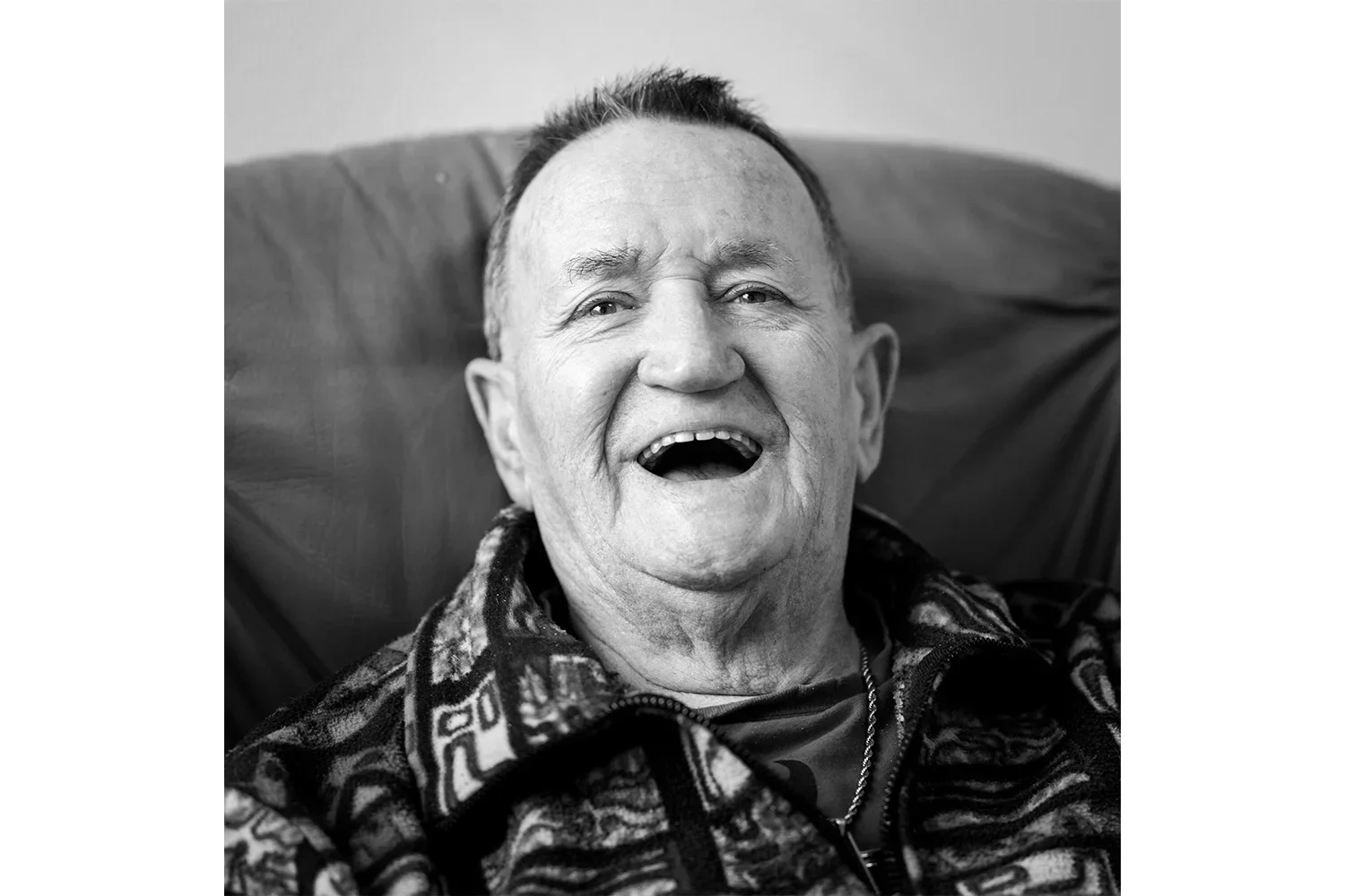 Portrait noir et blanc d'un homme âgé riant à pleines dents, photographie humaniste par Yann Lepora